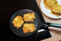 Golden-brown potato pancakes frying in a speckled non-stick pan on a hob Royalty Free Stock Photo