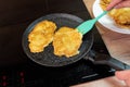 Golden-brown potato pancakes frying in a speckled non-stick pan on a hob Royalty Free Stock Photo