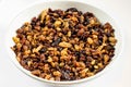 Golden and brown raisins in a small white ceramic plate on the white table