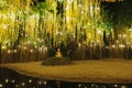 A golden Buddha sculpture underneath a tree and golden garlands Royalty Free Stock Photo