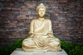 Golden Buddha statue against a brick wall background