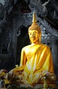 Golden buddha statue in front of metallic temple.