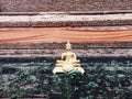 Golden Buddha statue sits on brick wall. Royalty Free Stock Photo