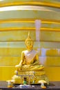 A Golden Buddha statue sits near a golden stupa in a Buddhist temple. Religion and traditions of Thailand Royalty Free Stock Photo