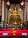 Golden Buddha statue on a throne with flowers in the Wat Arun Temple in Bangkok, Thailand