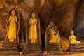 Golden buddha statues along the wall inside the cave