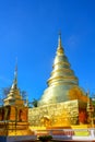 Golden Buddhist temple, shiny golden pagoda at Wat Pra Sing with blue sky background, Chiang-mai province northern of Thailand Royalty Free Stock Photo
