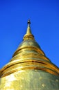 Golden Buddhist temple, shiny golden pagoda at Wat Pra Sing isolated on blue sky background, Chiang-mai, Thailand Royalty Free Stock Photo