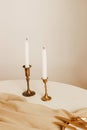 Golden candlesticks with white candles in a beige interior