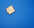 Golden cardboard gift square box tied with a ribbon on a dark blue background