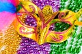 Golden carnival mask and colorful beads close-up. Mardi Gras or Fat Tuesday symbol. Royalty Free Stock Photo