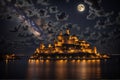 A golden light castle on a rock in the middle of the ocean