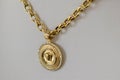 Golden chain necklace with medallion on white surface