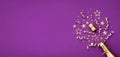 Golden champagne bottle with confetti stars and party decorations on purple background. Christmas, birthday or New Year card Royalty Free Stock Photo