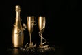 Golden champagne bottle and two glasses with ribbons on black background with copy space. new year party and anniversary Royalty Free Stock Photo