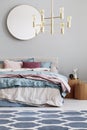 Golden chandelier above king size bed with blue, beige and pastel pink sheets