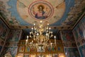 Golden chandelier inside an Orthodox church with saints' icons on the walls.