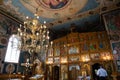 Golden chandelier inside an Orthodox church with saints' icons on the walls.