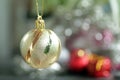 Golden Christmas ball ornament hanging on a blur tree bokeh light festive background. Closeup of single gold Christmas ball Royalty Free Stock Photo