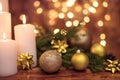 Golden Christmas ball on a tree branch, white candle flame with stars bokeh lights on a brown background Royalty Free Stock Photo