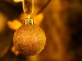 Golden glittering Christmas bauble close-up by blurred background