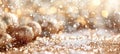 Golden Christmas baubles with glitter on a festive background. Sparkling gold ornaments with bokeh lights. Concept of Royalty Free Stock Photo