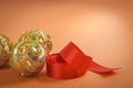 Golden christmas baubles and red ribbon on brown background Royalty Free Stock Photo