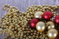 a Golden Christmas chain lies on the wooden table and on top of it there are traditional red and gold Christmas balls Royalty Free Stock Photo
