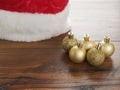 Golden Christmas and New years eve balls on a red Santa Claus hat on dark wood surface. Copy space. Winter holiday theme Royalty Free Stock Photo