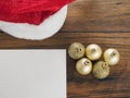 Golden Christmas and New years eve balls on a red Santa Claus hat on white surface, Blank white paper in the left bottom corner Royalty Free Stock Photo