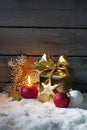 Golden christmas present, christmas ball, candle on pile of snow against wooden wall Royalty Free Stock Photo