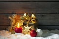 Golden christmas present, christmas ball, candle on pile of snow against wooden wall Royalty Free Stock Photo