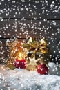 Golden christmas present, christmas ball, candle on pile of snow against wooden wall Royalty Free Stock Photo