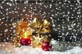 Golden christmas present, christmas ball, candle on pile of snow against wooden wall Royalty Free Stock Photo