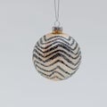 Golden Christmas tree ball covered with black zigzag patterns and glitter