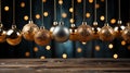 Golden Christmas tree balls hang over a wooden table, side view