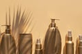 Golden clean bottles of cosmetics, sun shade from palm leaf on beige background. Cosmetic mock up bottles, tubes. Branding Royalty Free Stock Photo