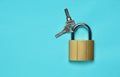 Golden closed lock with keys on a blue background. Copy space. Top View. Royalty Free Stock Photo