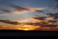 Golden clouds in the sunset sky over a spring field covered with snow Royalty Free Stock Photo