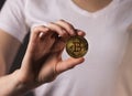 Golden coin of BTC or bitcoin held bu female hand