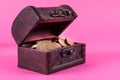 Coins in an old wooden box on a pink background Royalty Free Stock Photo