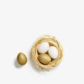 Golden color eggs in nest from straw on white background. Stylish gold egg for easter spring holiday. Top view Royalty Free Stock Photo