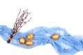 Golden colored Easter eggs with willow catkins branches on light blue gauze fabric isolated on white background. Top view. Royalty Free Stock Photo