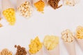 Golden colorful snacks - nachos, popcorn, croutons, chips in craft paper cone as border on white wood table with copy space.