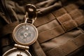 Golden compass on tactical or travel backpack, shallow DOF, focus on dial. Concept for direction, travel, guidance or assistance