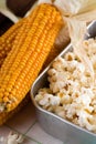 Golden corncob next to pan with popcorn