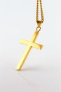 Golden cross pendant on the gold chain on white background