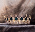 Golden crown with green emeralds stones, crystals. Luxury