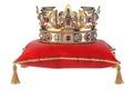 Golden crown with jewels on red velvet pillow for coronation isolated on white