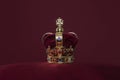 Golden crown on a velvet cushion on a deep red background with copy space Royalty Free Stock Photo